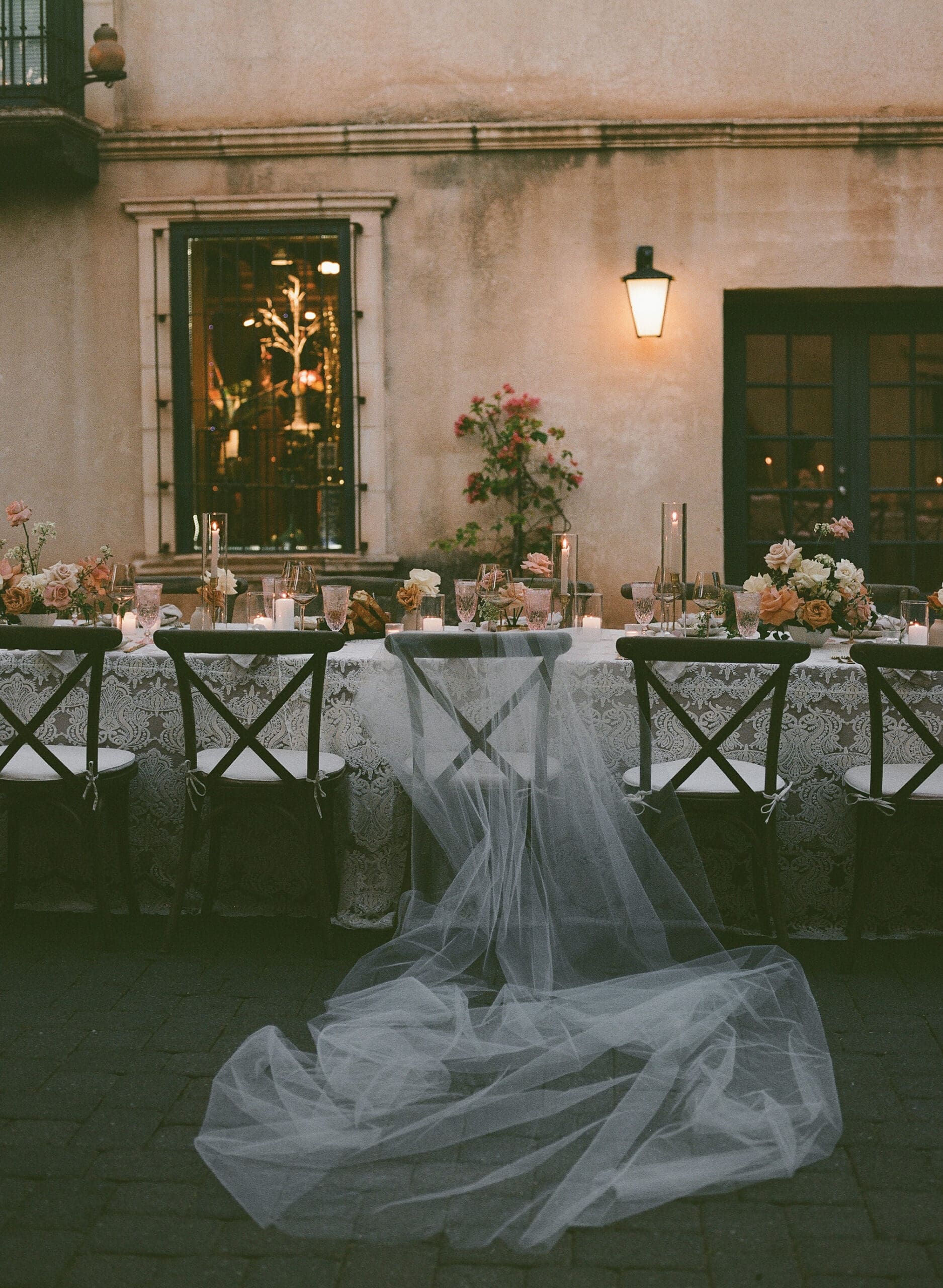 Outdoor wedding reception table with blush and cream floral centerpieces, taper candles, and gold vessels at an Arizona courtyard venue